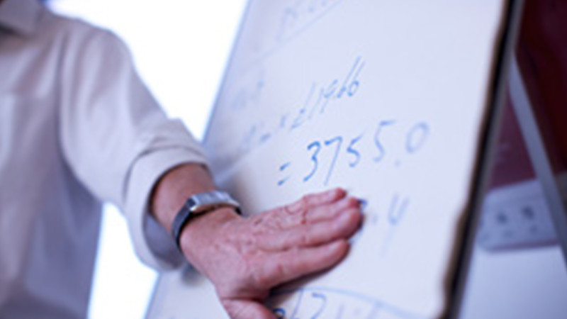 A person pointing to writing on a board